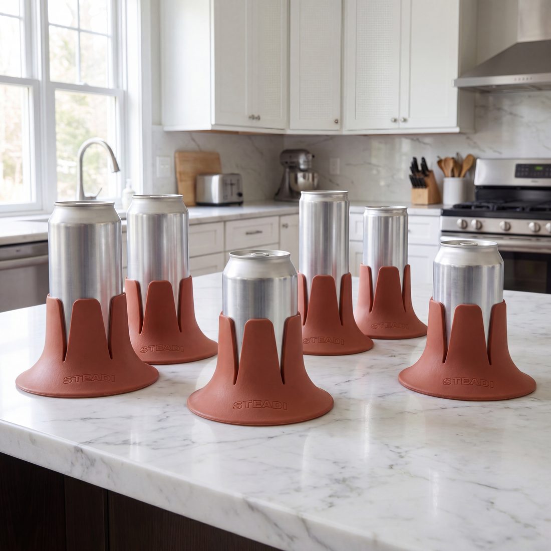 Six cans of different sizes, each standing in a terracotta Steadi, along a kitchen counter.